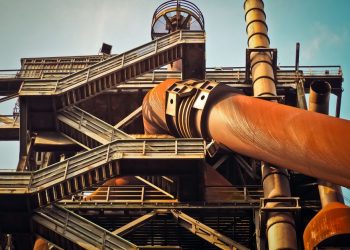 Close-up view of a rusty industrial structure with large pipes and steel framework, showcasing industrial decay.