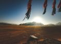A stunning sunrise over solar panels in a vast desert landscape with mountains in the background.