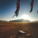 A stunning sunrise over solar panels in a vast desert landscape with mountains in the background.