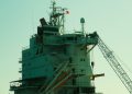 Close-up of an industrial ship's structure and crane against a sunset backdrop.