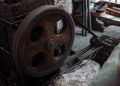 Close-up of a rusted industrial machine wheel in an old workshop setting.