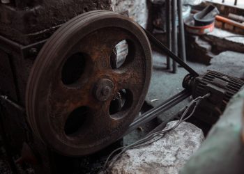 Close-up of a rusted industrial machine wheel in an old workshop setting.