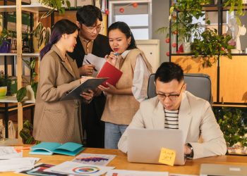 Group of young professionals collaborating in a modern, plant-filled office.