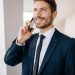 Confident businessman in suit making a phone call indoors, smiling.
