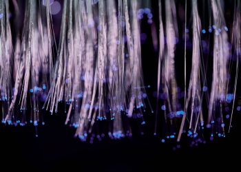 Close-up of glowing fiber optic lights with a purple and blue bokeh effect.