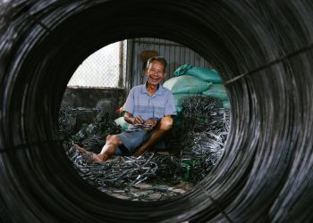 Portrait of a senior man smiling while handling wires in an industrial setting.