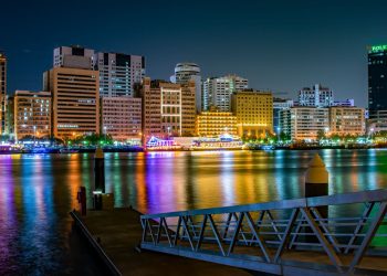 A stunning view of Dubai's illuminated skyline at night with colorful reflections on the waterfront.