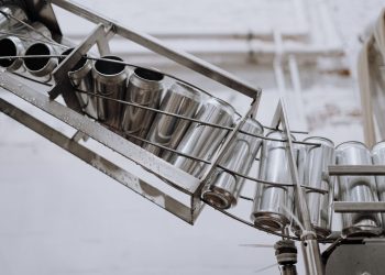 Conveyor belt with empty aluminum cans in a factory setting, showcasing production equipment.