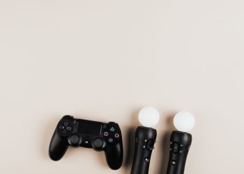Black gaming controllers arranged on a light background with ample copy space.