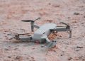 Close-up of a modern drone resting on sandy terrain, highlighting technology and exploration.