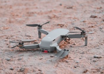 Close-up of a modern drone resting on sandy terrain, highlighting technology and exploration.