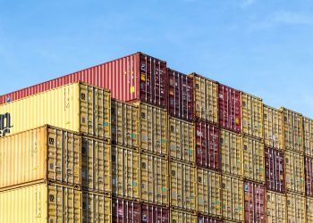 Colorful stacked cargo containers in Hamburg port under a clear blue sky.