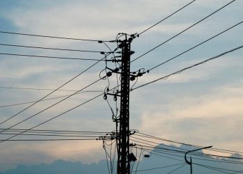 Silhouette of power lines and pole against a vibrant sunset sky.