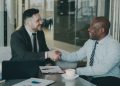 Two businessmen shaking hands over a deal at a modern office.