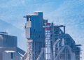 Aerial view of a modern industrial factory with mountains in the background, showcasing advanced architecture.
