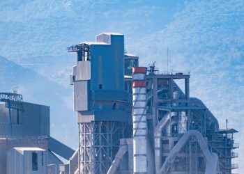 Aerial view of a modern industrial factory with mountains in the background, showcasing advanced architecture.