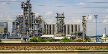 Image of a large chemical factory in Schwechat, Austria, showcasing industrial pipes and machinery.