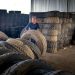 Man organizing large industrial tires in a warehouse, showcasing labor and storage setup.
