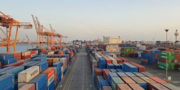 A bustling port scene with colorful cargo containers at sunrise. Ideal for logistics concepts.