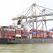 Cargo vessel moored at Kochi, Kerala, India, showcasing global container shipping with cranes in background.