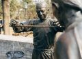 Bronze statues depicting traditional Chinese weighing scales at an outdoor market.