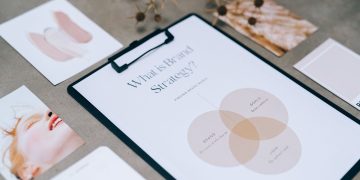 A close-up view of a brand strategy document on a desk surrounded by design artworks.