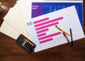 Top view of market research reports and calculator on a wooden desk, illustrating business analysis.